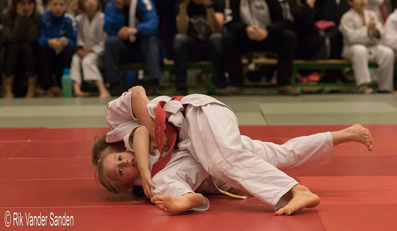 Deux jeunes judokas en combat au sol lors d'une rencontre