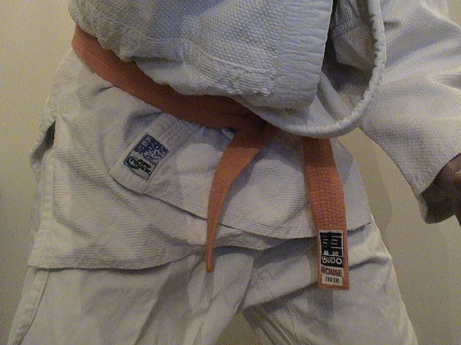 Ceinture orange de judo nouée sur un judogi blanc