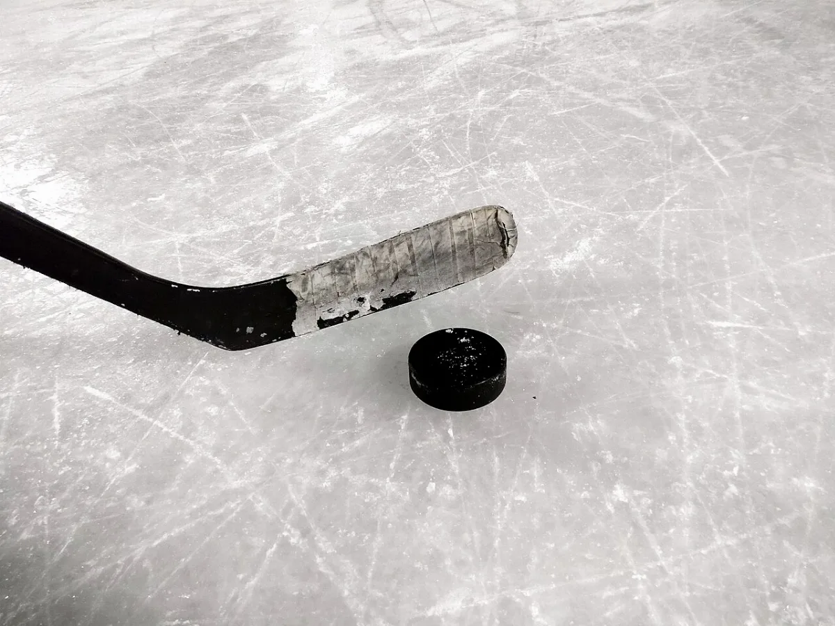 Lame de crosse de hockey avec ruban adhésif et palet sur la glace