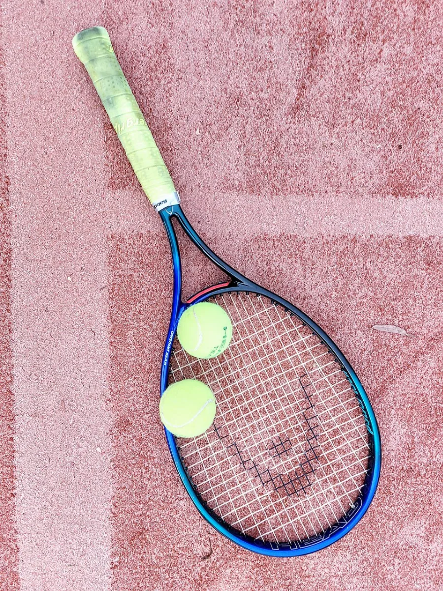 Raquettes et balles de tennis posées sur un court en terre battue