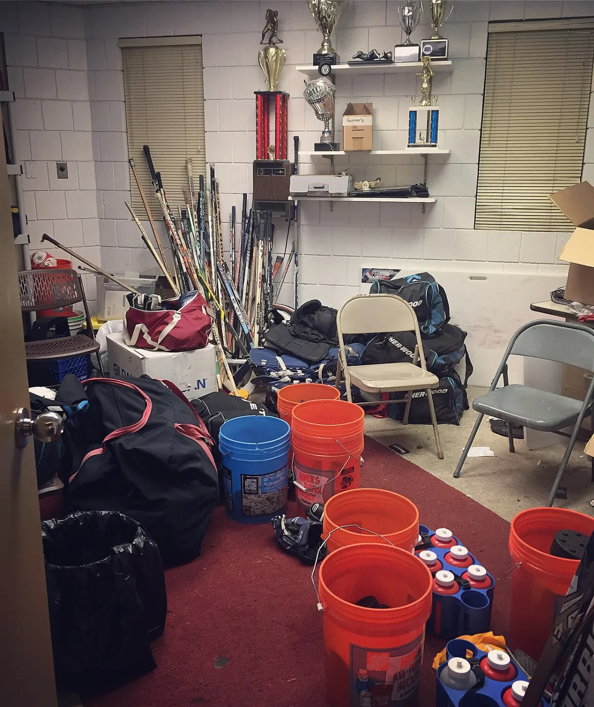 Local de matériel d'un club de hockey avec crosses, sacs et porte-gourdes